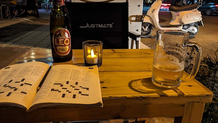 scene of a white mug of coffee, scene of a crossword puzzle and cold Thai beer