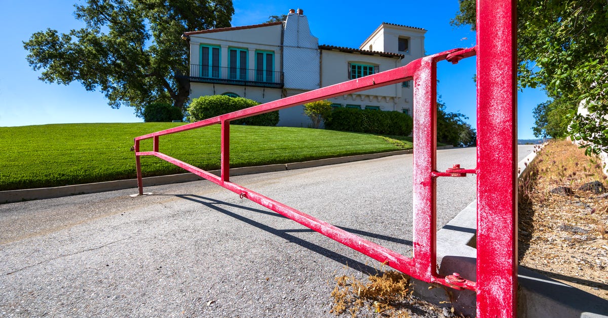 Photo: David Brown / Pexels A bold red gate on a sunny day, marking the entrance to a beautiful hillside residence.
