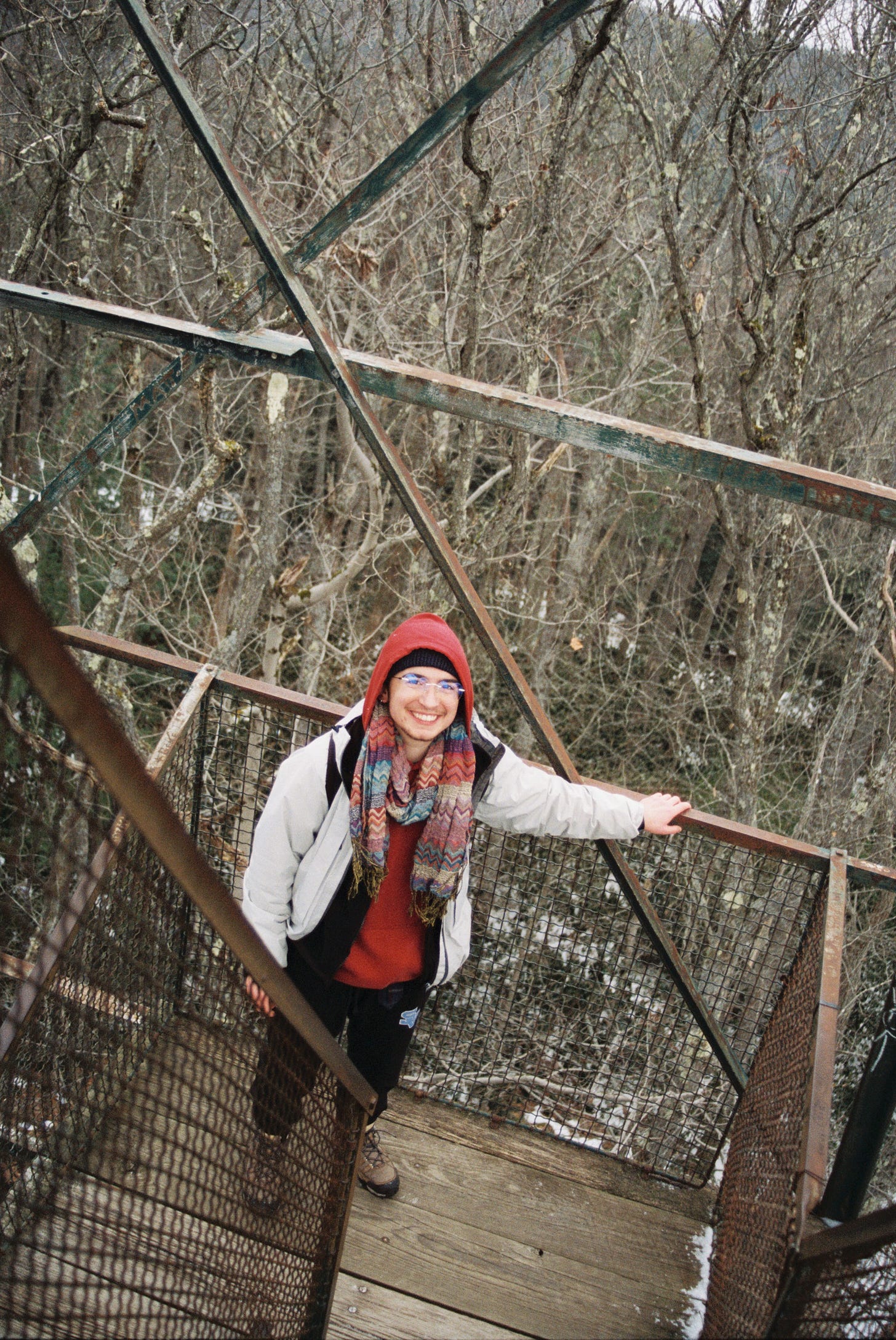 An image of me bundled up on a lower platform of the fire tower. I am holding on to the railing and smiling wide.