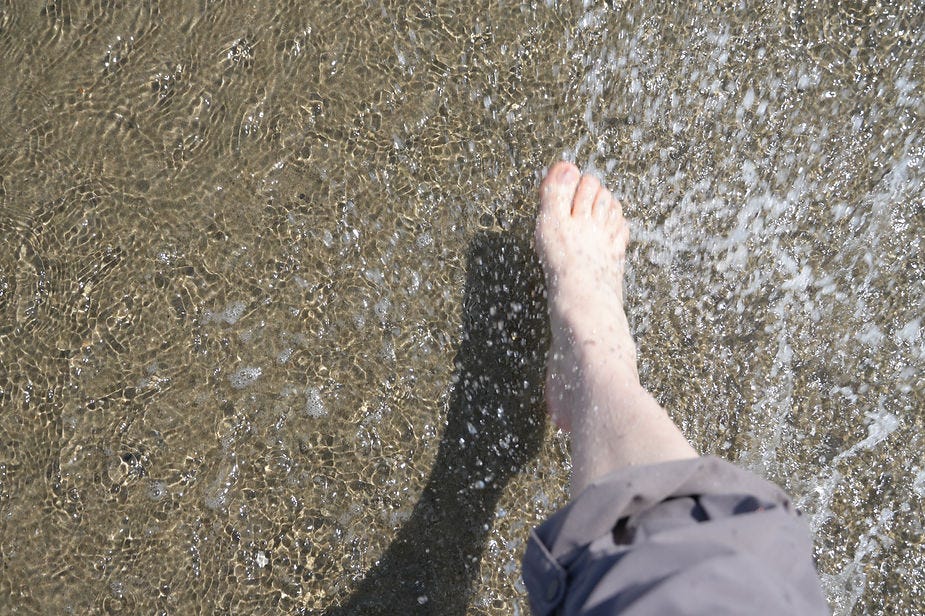 A foot kicks through water, throwing up droplets and creating ripples.