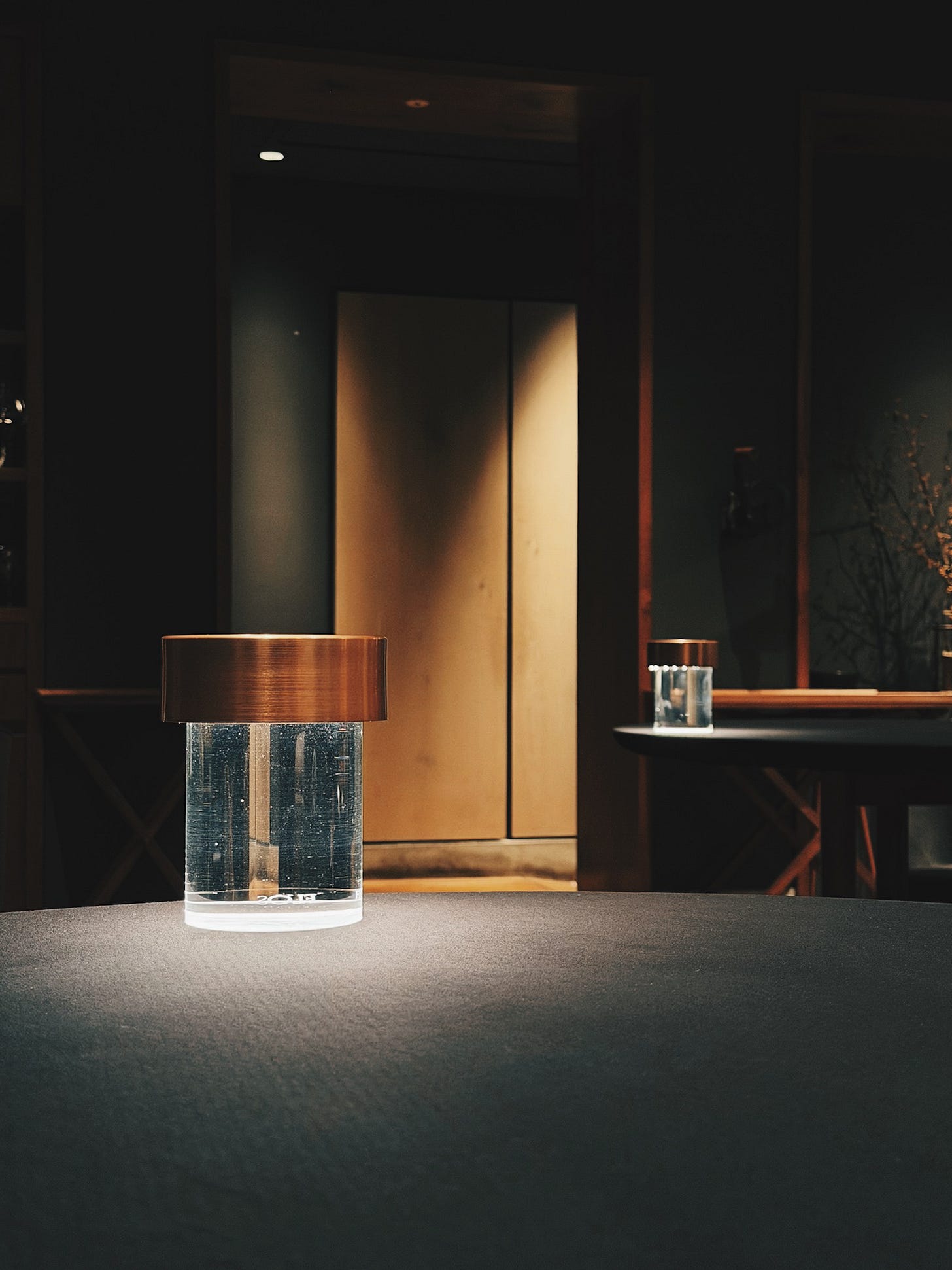Minimalist table setting with copper lamp at La Cime restaurant in Hommachi, Osaka showing modern Japanese interior design.