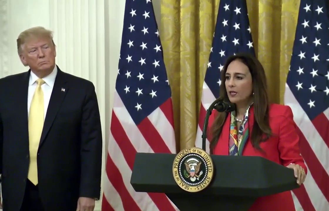 Harmeet Dhillon speaks at a White House lectern as President Donald Trump looks on.