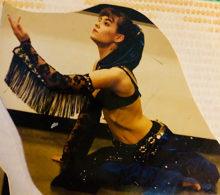 Fringe, coins, sequins and lace. A shot of my hips in a spangly red belly dance belt, and posed on the floor in blue-and-black, one arm and gaze uplifted, light and focus back in my eyes.
