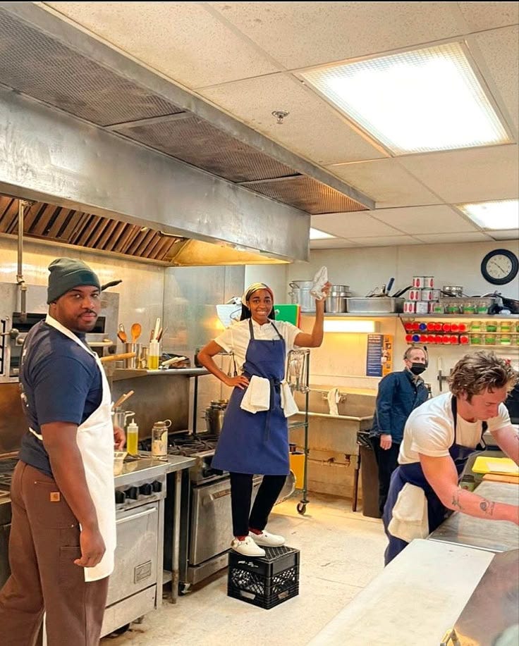 This may contain: a group of people in a kitchen preparing food