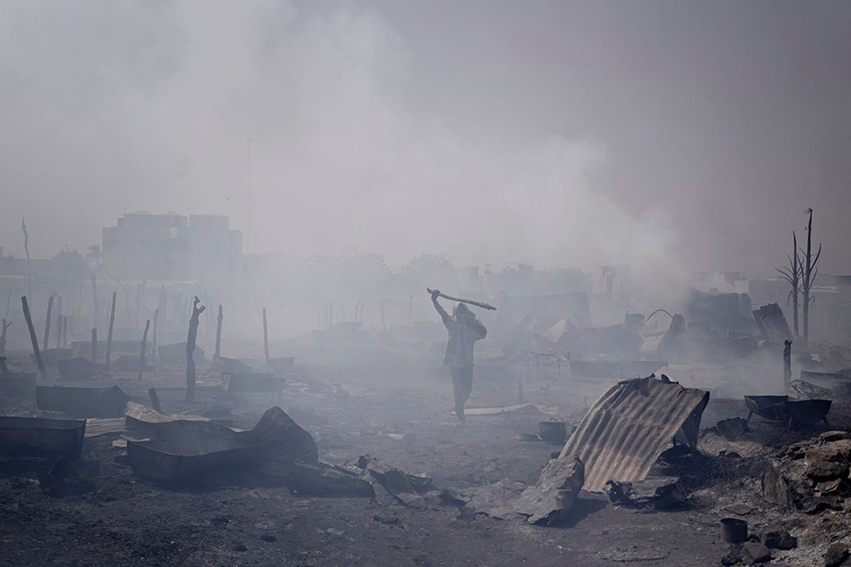 A man walks through a burned out village full of smoke. A man walks through a burned out village full of smoke.