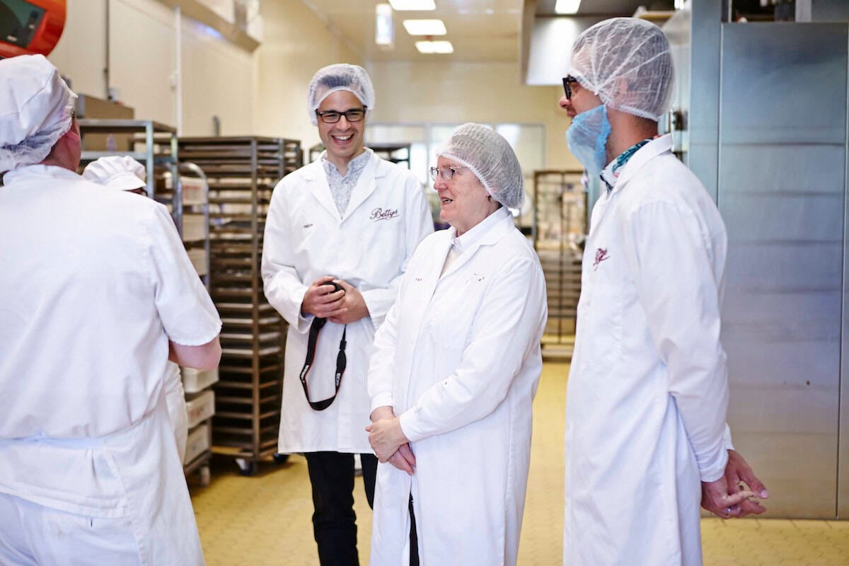 People touring Bettys Craft Bakery. Group of people wearing white coats in Bettys bakery.