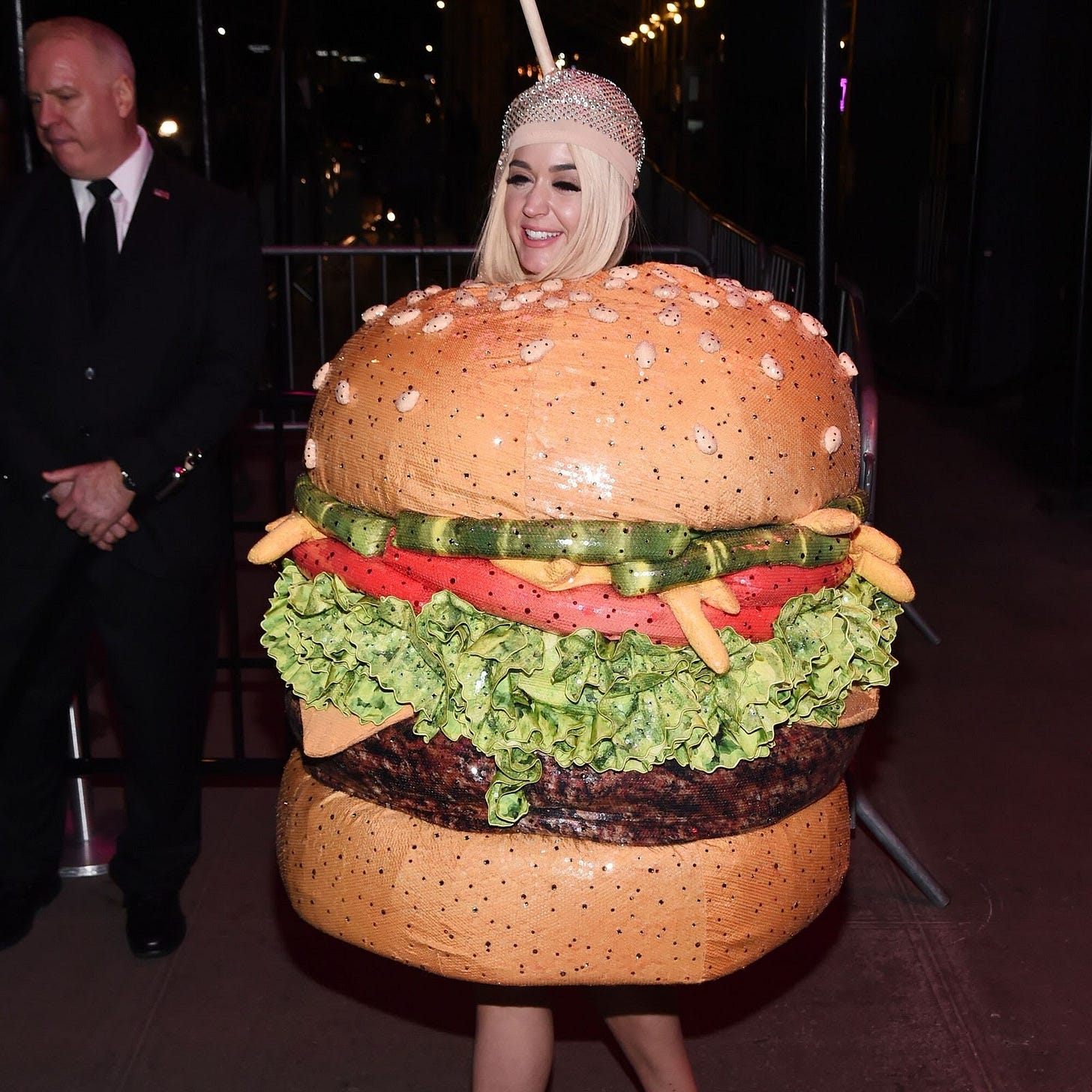 Image may contain Human Person Burger Food Clothing Overcoat Suit Coat Apparel Birthday Cake Dessert and Cake