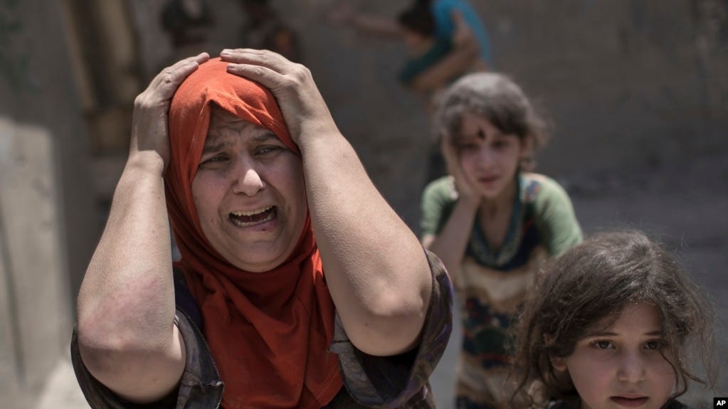 FILE - A woman screams while fleeing with her family through a destroyed alley, as Iraqi special forces continue their advance against Islamic State group militants, in the Old City of Mosul, Iraq, July 2, 2017.