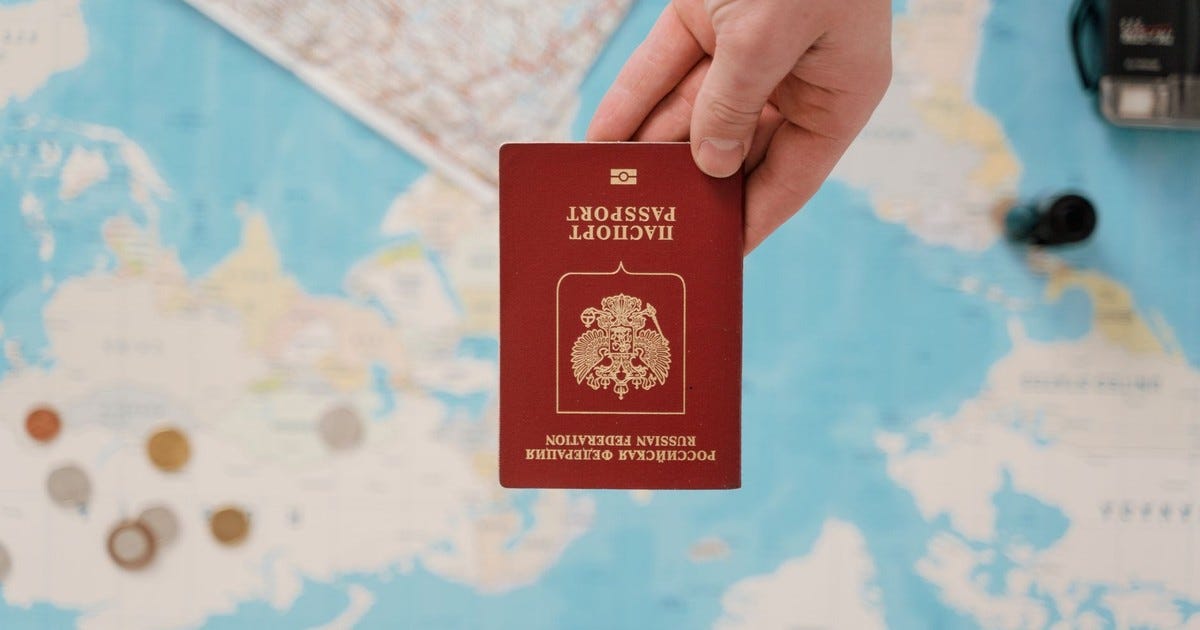 A hand holding a Russian passport above a travel-themed map, capturing world travel concepts.