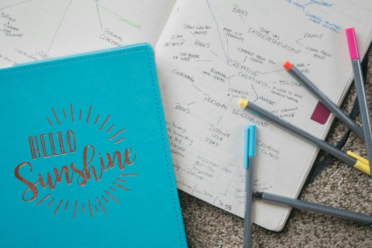 Having Trouble Creating a Journaling Habit? Try This! Blue journal with the words "Hello Sunshine" on the cover and markers