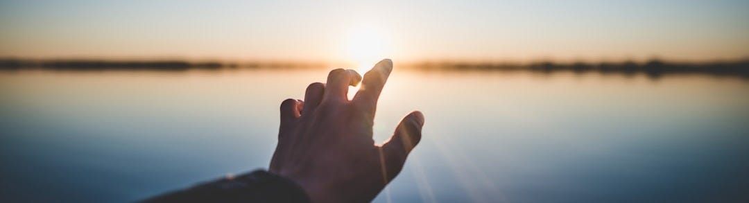 landscape photography of person's hand in front of sun landscape photography of person's hand in front of sun