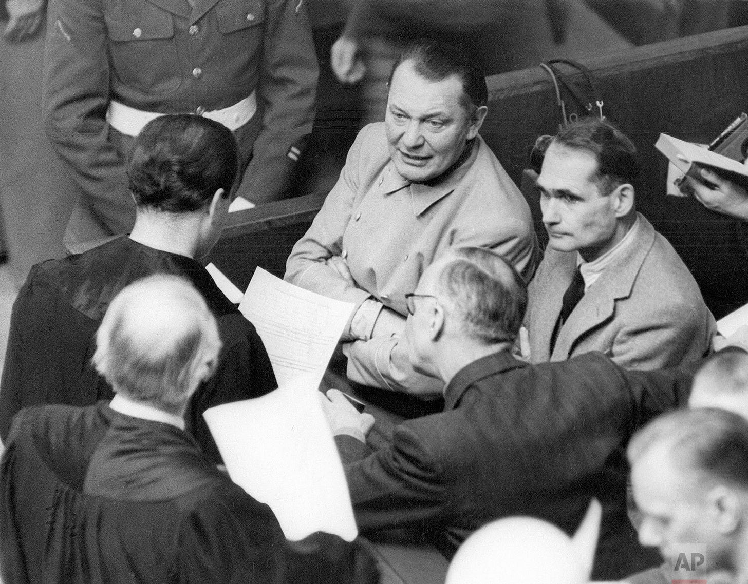 Rudolf Hess, right, engages in a discussion during a Nuremberg trial recess, having requested permission to act as his own attorney. He confers with Goering and other defendants, highlighting the dramatic courtroom dynamics. Rudolf Hess, right, engages in a discussion during a Nuremberg trial recess, having requested permission to act as his own attorney. He confers with Goering and other defendants, highlighting the dramatic courtroom dynamics.