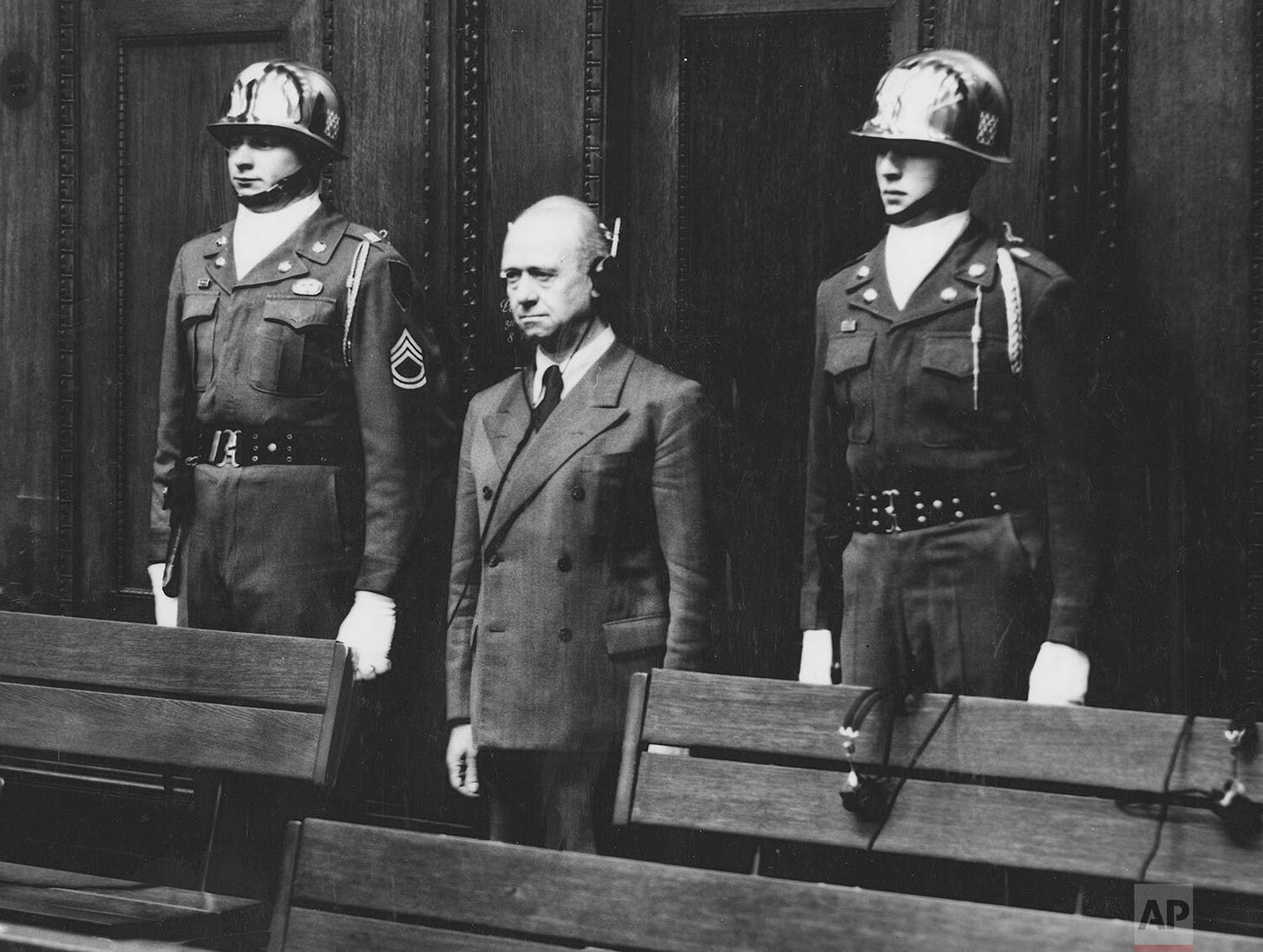 Paul Koerner receives a 15-year prison sentence, flanked by U.S. Army honor guards Sgt. Thomas H. Andress and Pfc. Bobbie G. Senior, members of the 16th Infantry Regiment, at the Nuremberg trials.