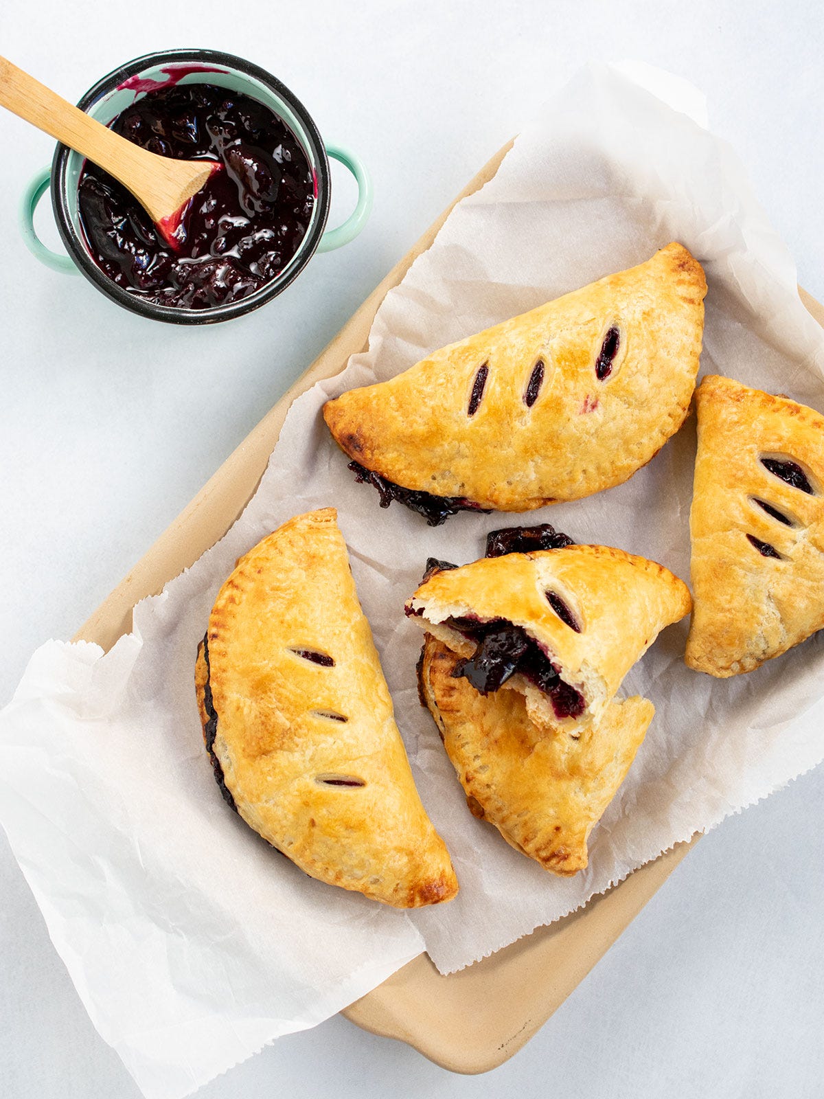 Mini cherry pies with pie filling in a small blue bowl with a spoon.