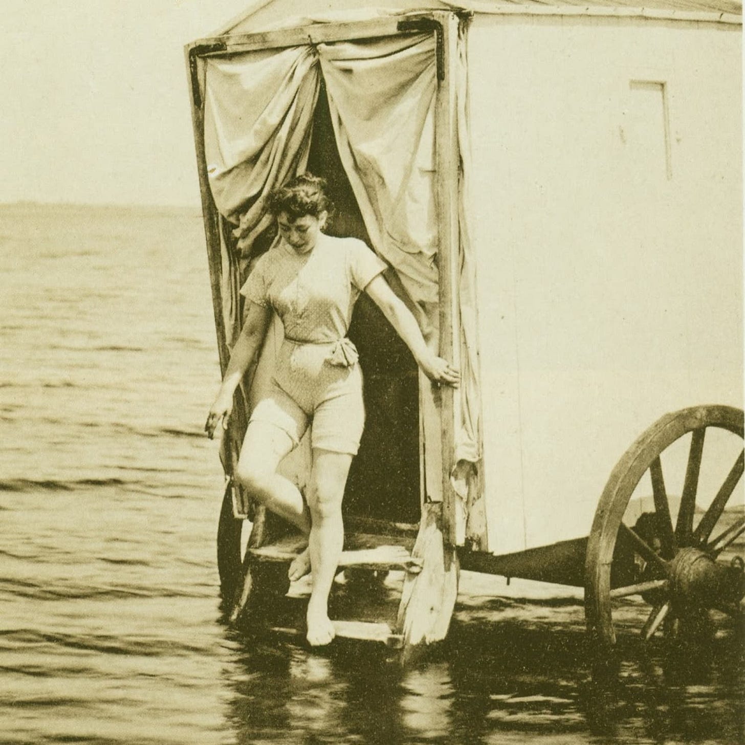 Sepia Victoriann photograph of a woman exiting a Bathing Machine into the water