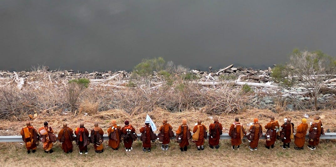 Monks in orange robes holding hands by water Monks in orange robes holding hands by water
