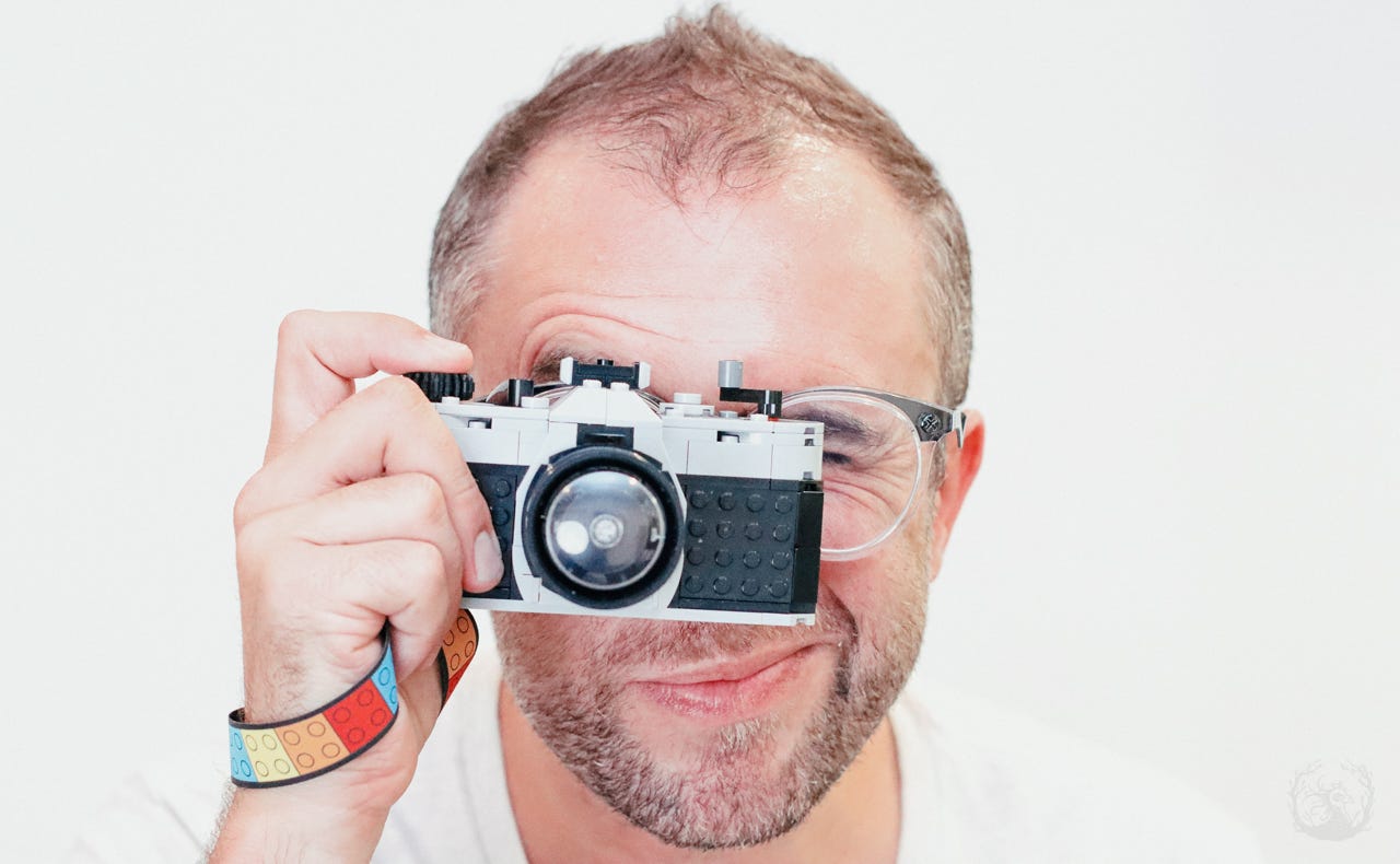 A photograph of the author, Lucas Van Wyk Joel, holding a toy LEGO camera.