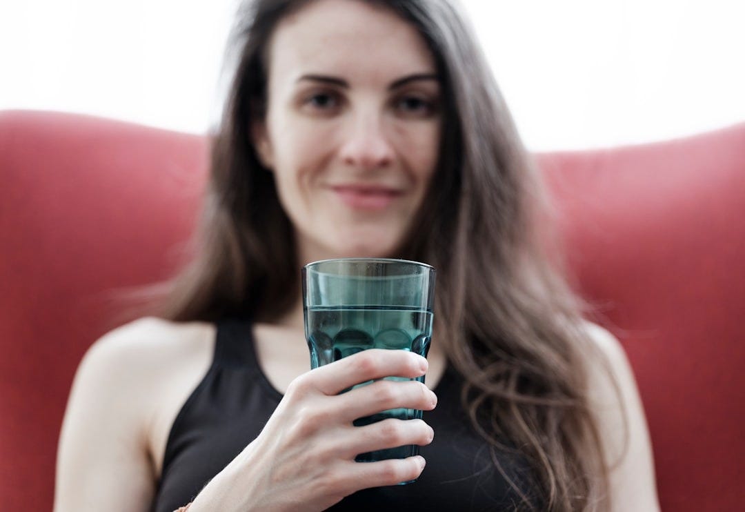 a woman holding a glass of water in her hand
