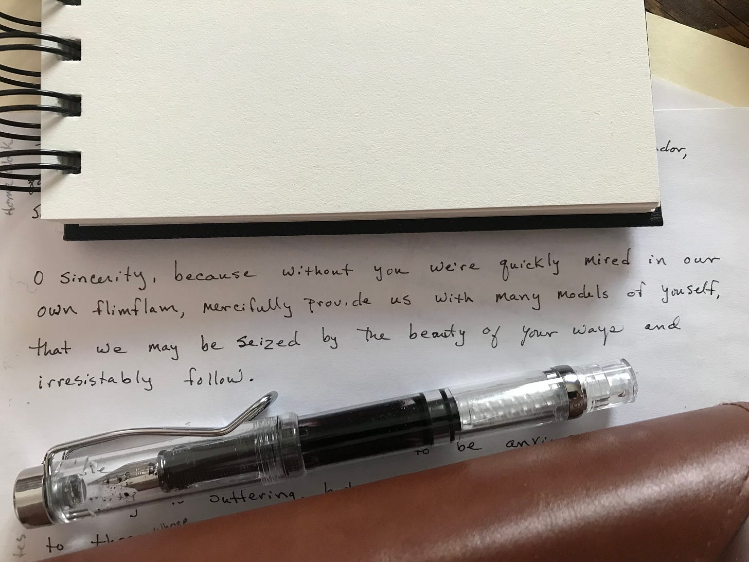 A fountain pen laying on top of a notebook page. On the page is handwritten the text of this little prayer.