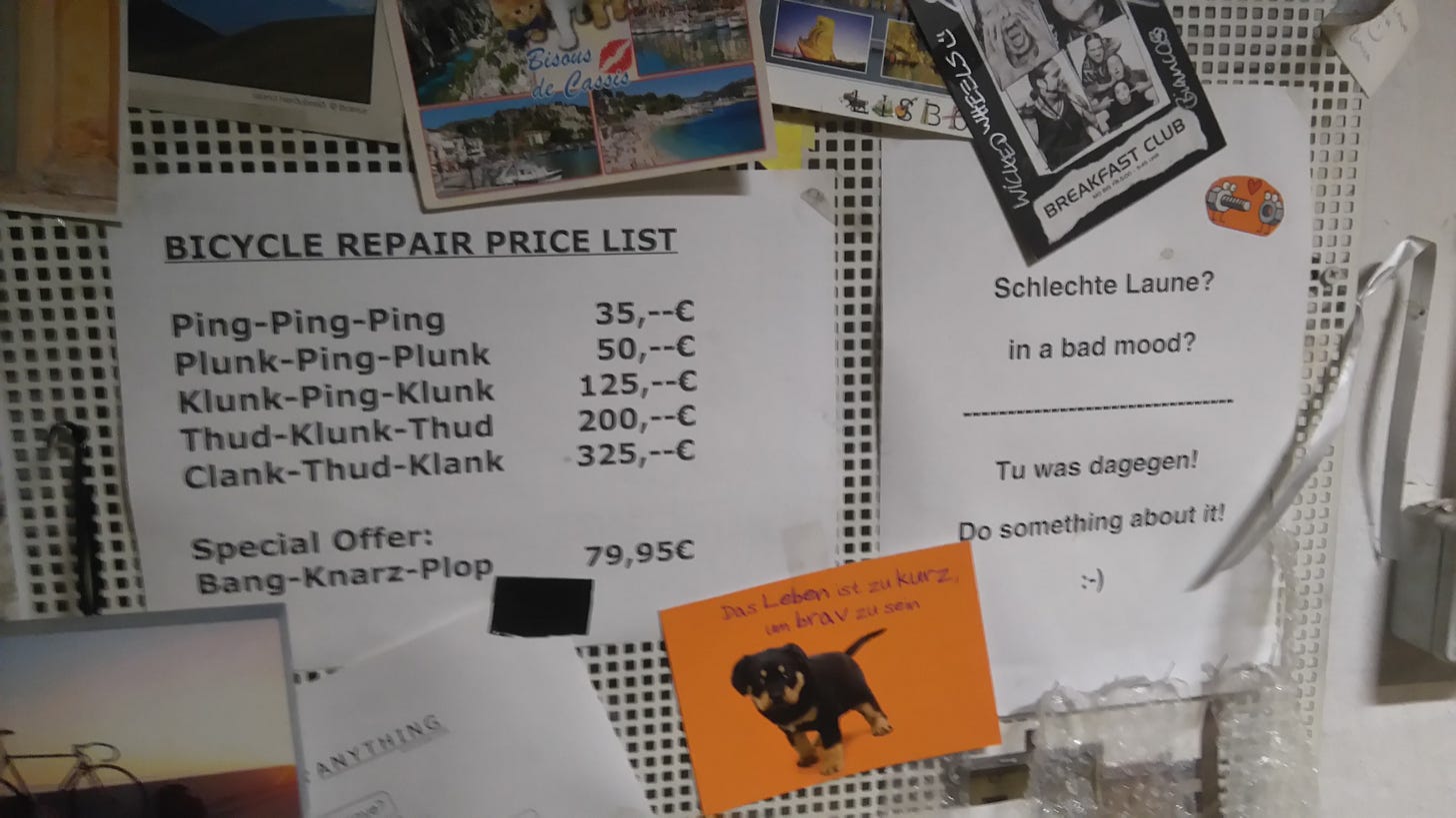 Wall display of a bike shop repair price list in Berlin, showing service costs based on cartoonish bike noises like “Ping-Ping-Ping” and “Clank-Thud-Klank.”