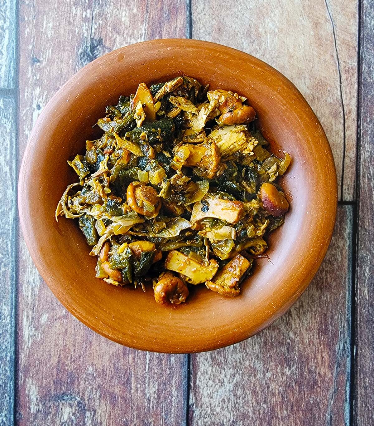 A bowl of Tarahumara mushrooms and chiles on a wooden table. 