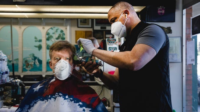 A stylist wearing a protective mask cuts a customer's hair at a barbershop in Atlanta, Georgia, U.S., on Monday, April 27, 2020. A stylist wearing a protective mask cuts a customer's hair at a barbershop in Atlanta, Georgia, U.S., on Monday, April 27, 2020.