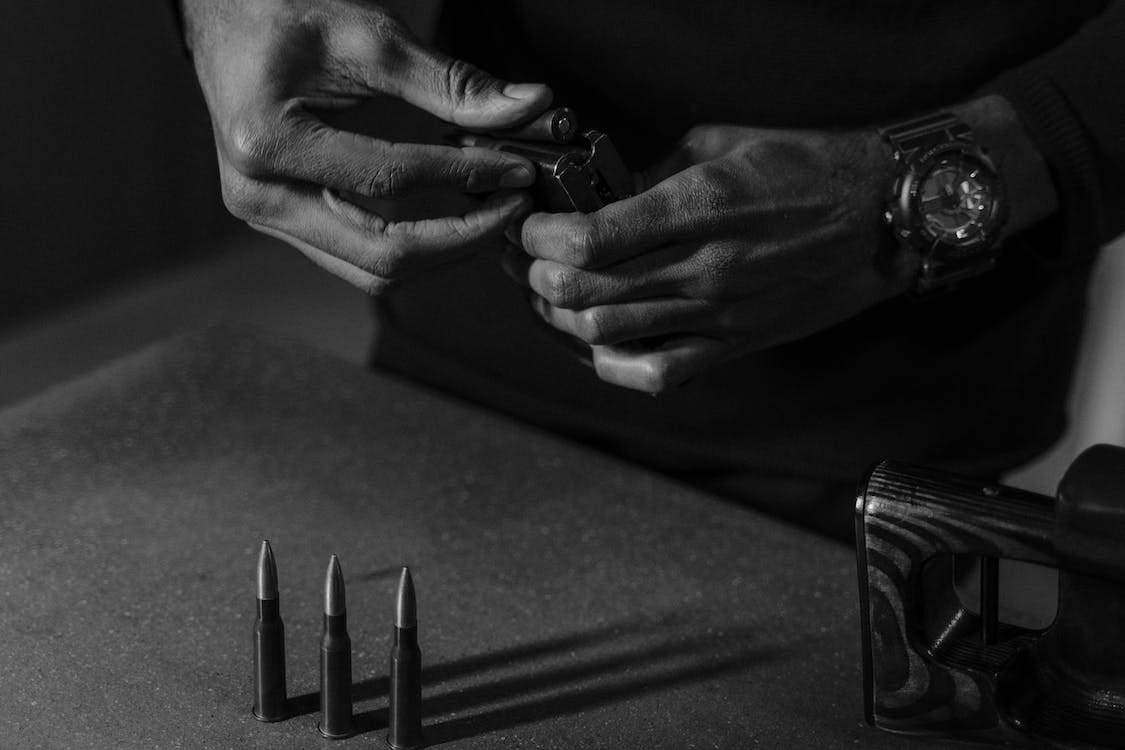 Free Person Holding a Bullet and a Gun Magazine Stock Photo