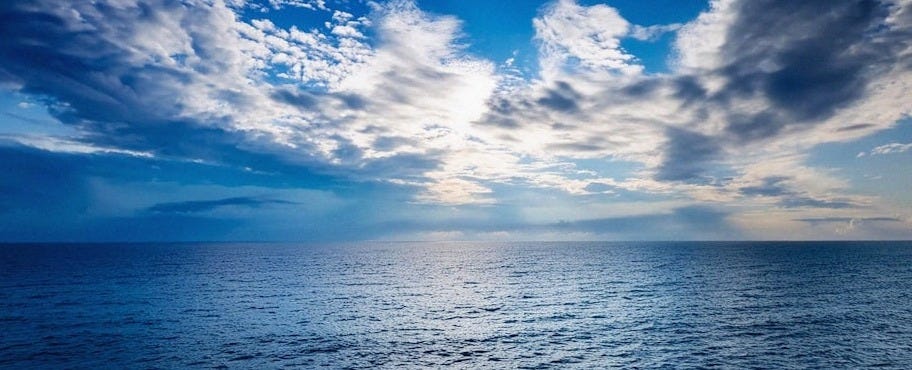 The sun is shining through the clouds over the ocean