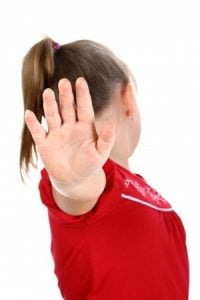 A young girl in a red dress holding her hand up saying no.