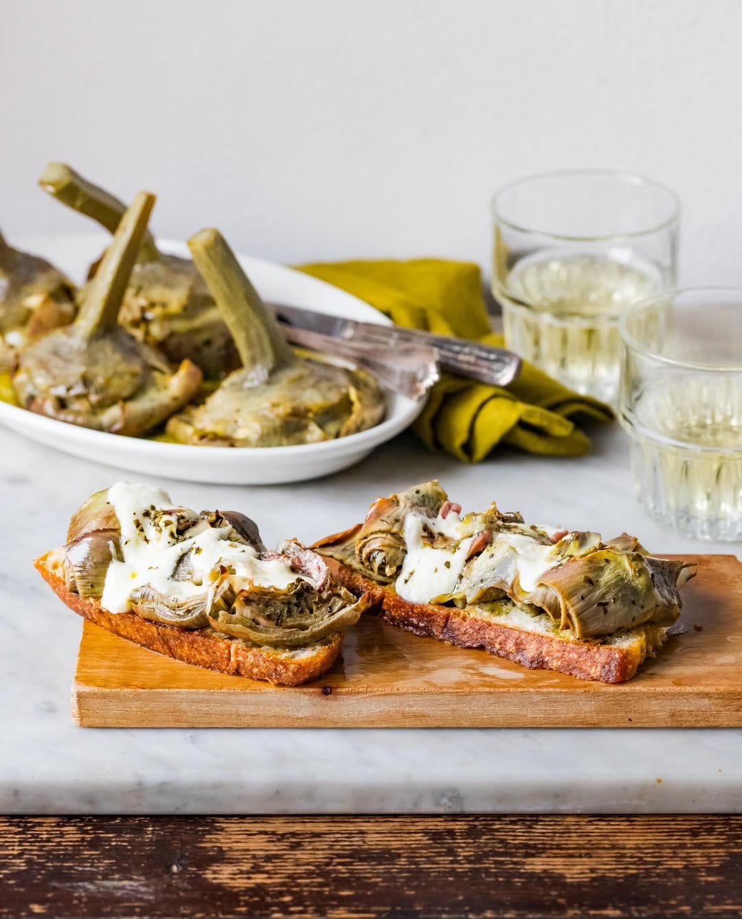 crostini with artichokes on a wooden board and two glasses of wine crostini with artichokes on a wooden board and two glasses of wine