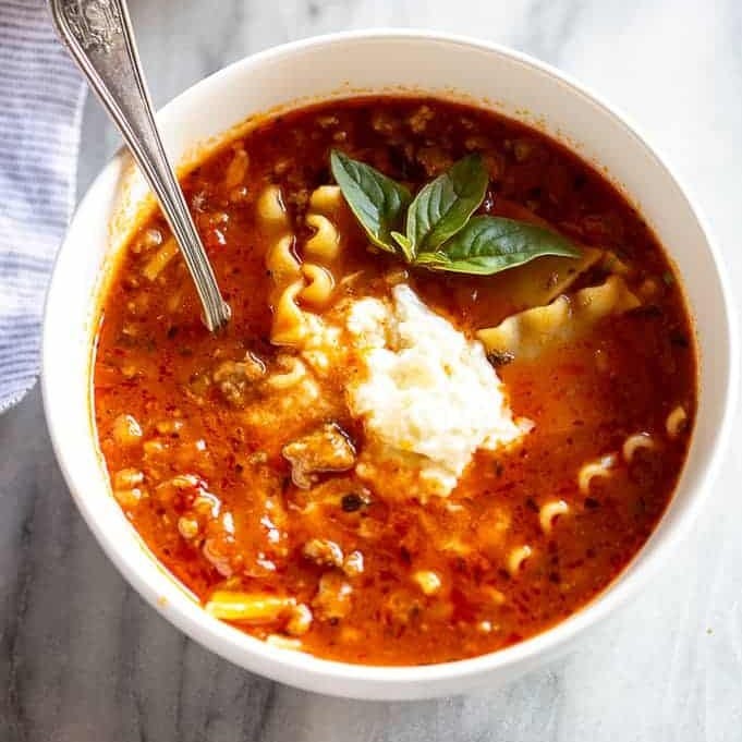 Lasagna Soup with a scoop of ricotta cheese on top and a spoon in the bowl.