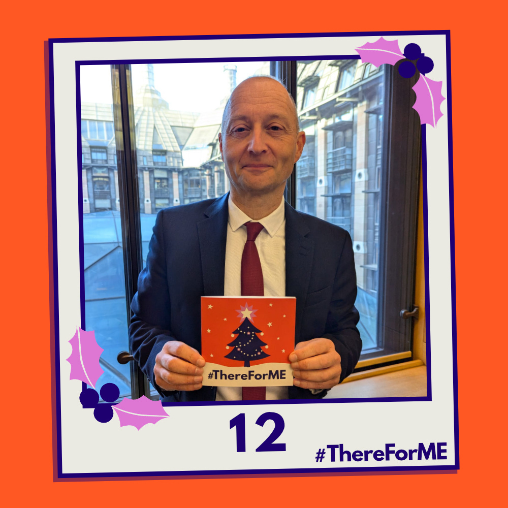 A pretend polaroid shows a smiling Paul Waugh MP posing for a photo holding a #ThereForME Christmas card.   The image on the card shows the dark blue Christmas tree, decorated with sparkling fairy lights, baubles and a star on the top, in a snowy landscape against a starry backdrop. The design is in the #ThereForME colours.