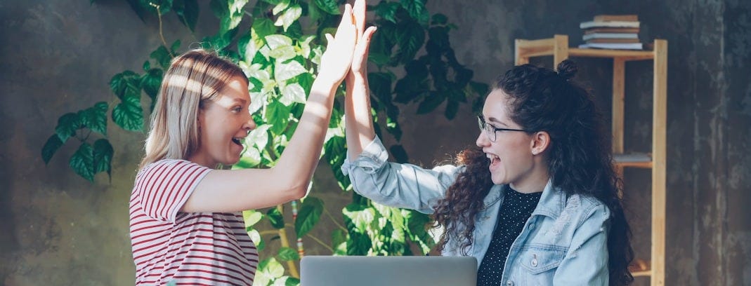 Two women celebrate success with a high five.