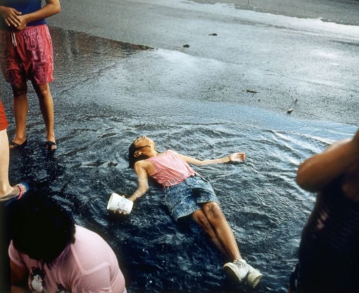 This may contain: people are standing in the water and one person is laying on the ground