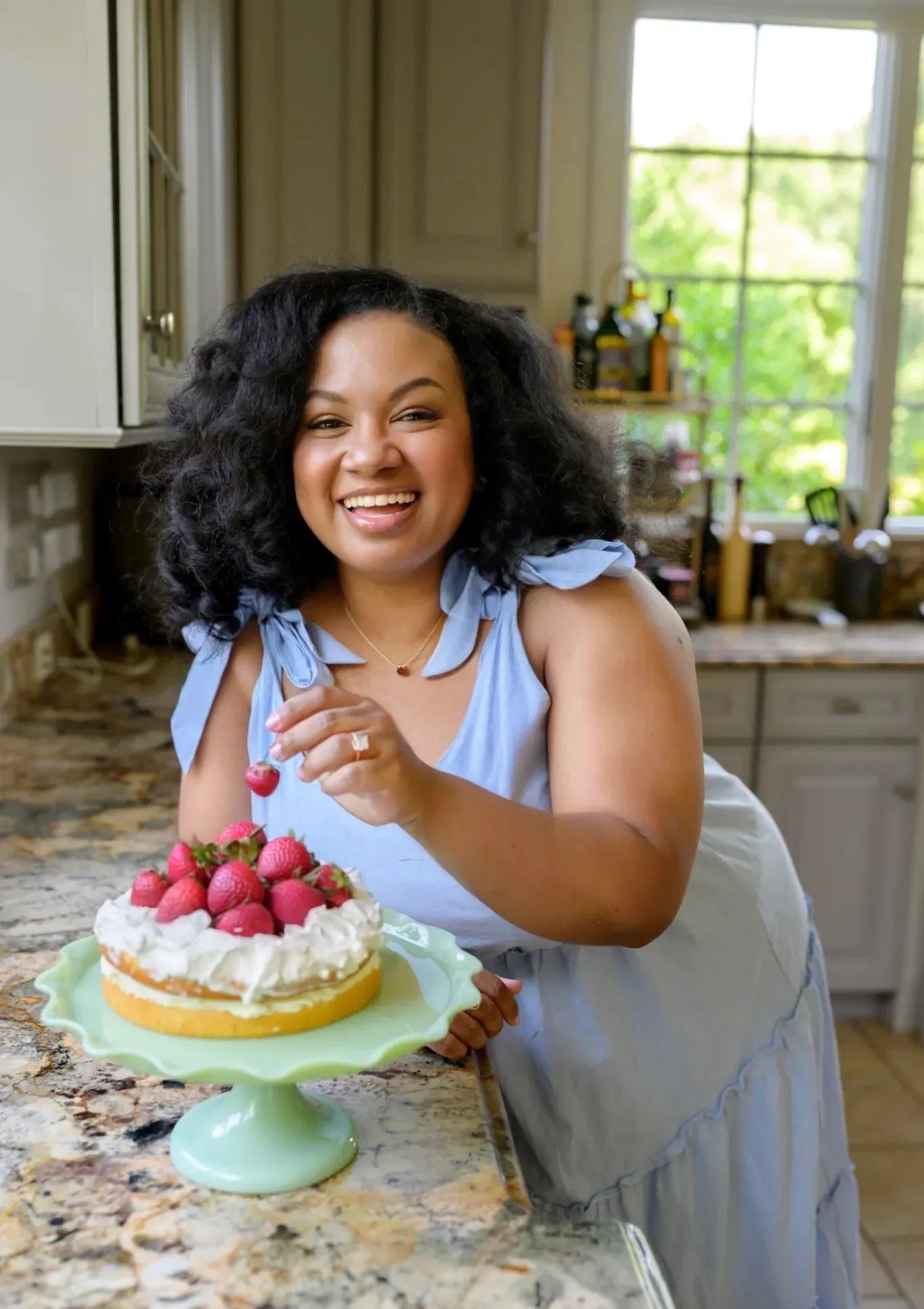 Eden Westbrook standing in her kitchen with a cake topped with strawberries Eden Westbrook standing in her kitchen with a cake topped with strawberries