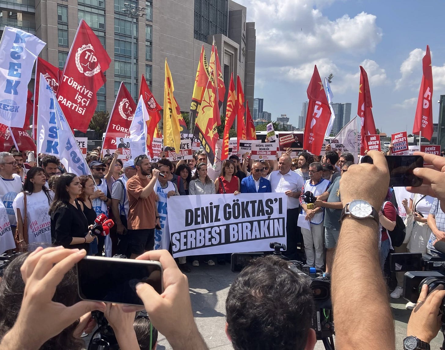 Çağlayan'da basın açıklaması. Kalabalık, flamalar. Önde bir pankart: "Deniz Göktaş'ı serbest bırakın" yazıyor.