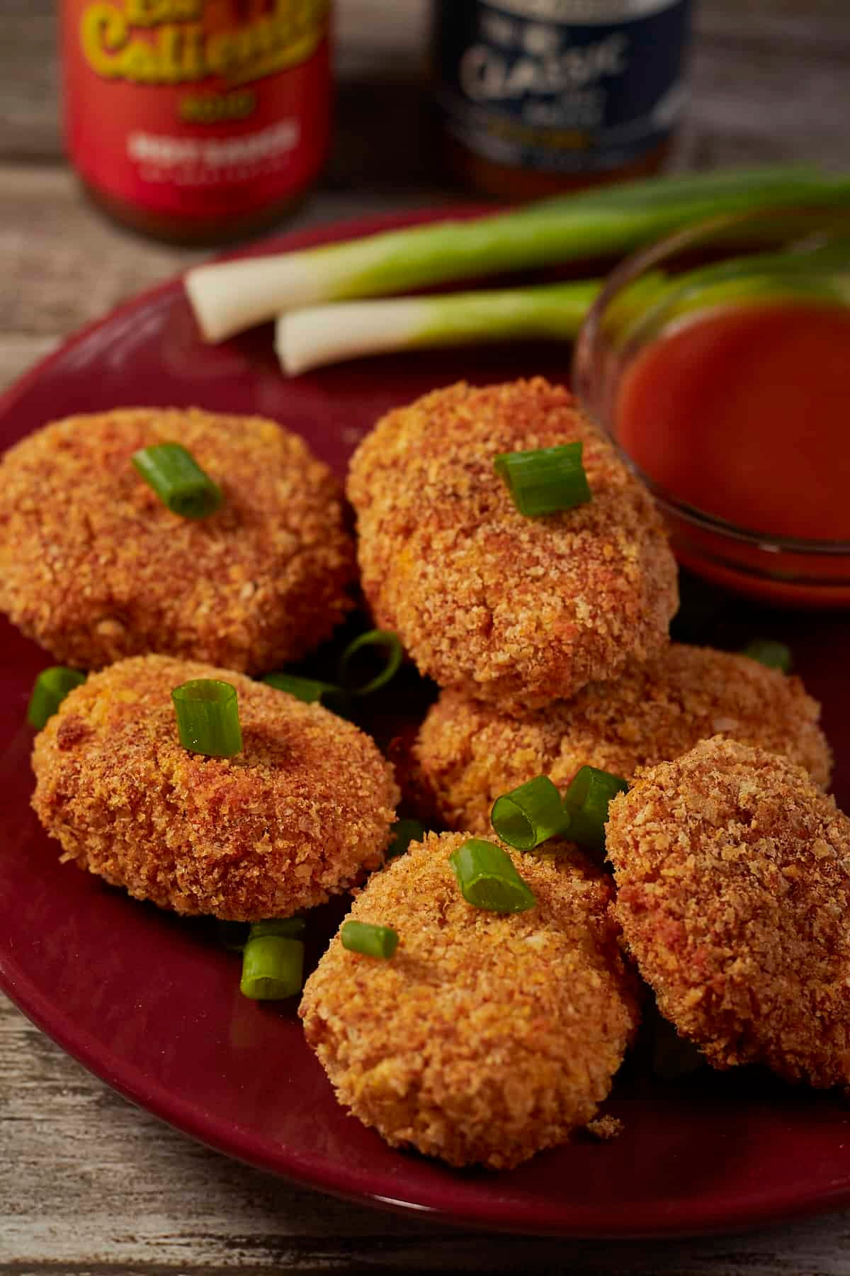 a plate of spicy vegan chickpea nuggets with sauce and green onions