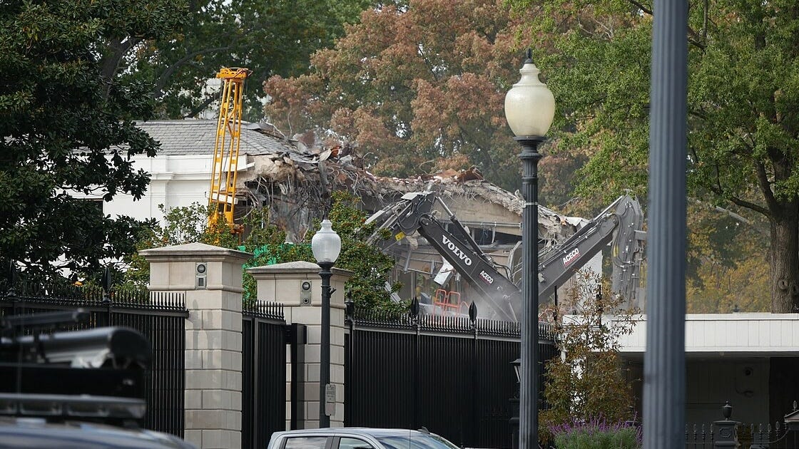 The partially demolished East Wing and construction equipment behind a wrought iron fence. 