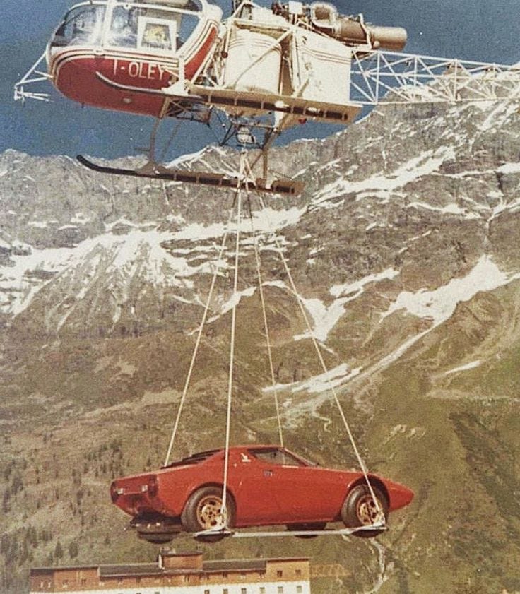 This may contain: a red car being lifted by a helicopter This may contain: a red car being lifted by a helicopter