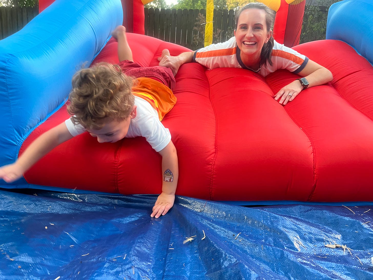 A mom and her son sliding face first down a bounce house