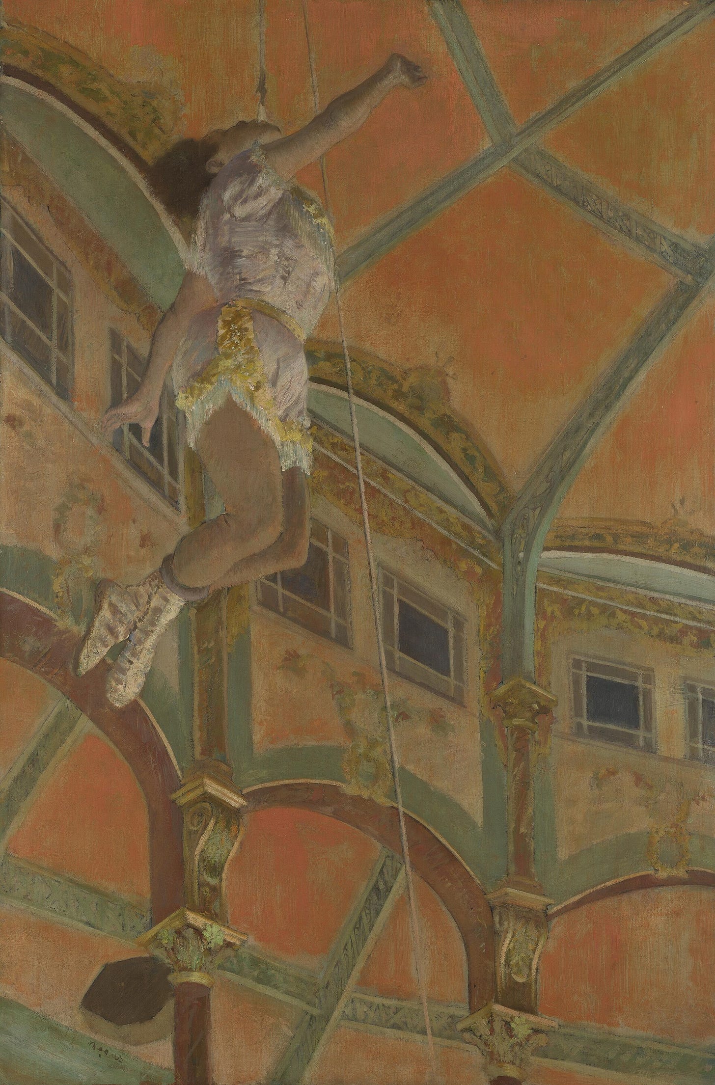 Seen from far below, a woman in a pale costume hangs high under the orange and green dome of a circus, her arms and legs bent, held only by a rope clenched in her teeth.