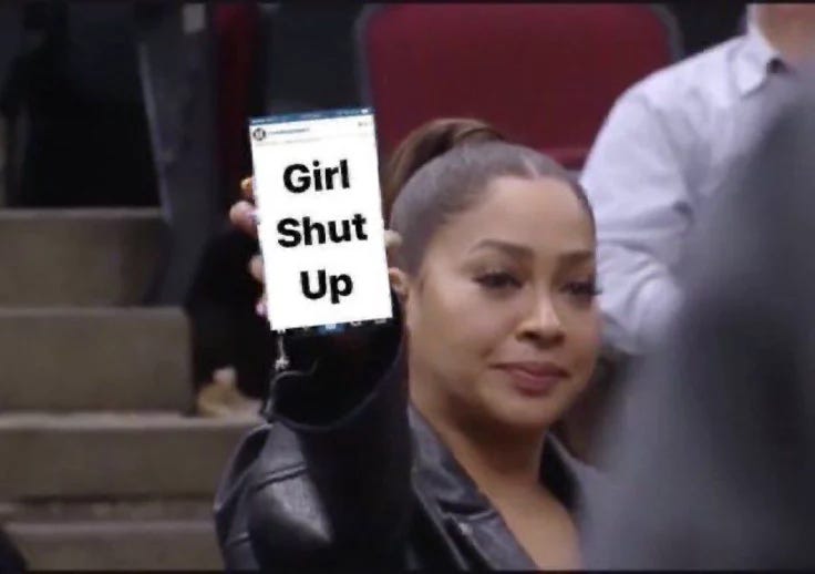 This may contain: a woman holding up a sign with the words girl shut up in front of her This may contain: a woman holding up a sign with the words girl shut up in front of her