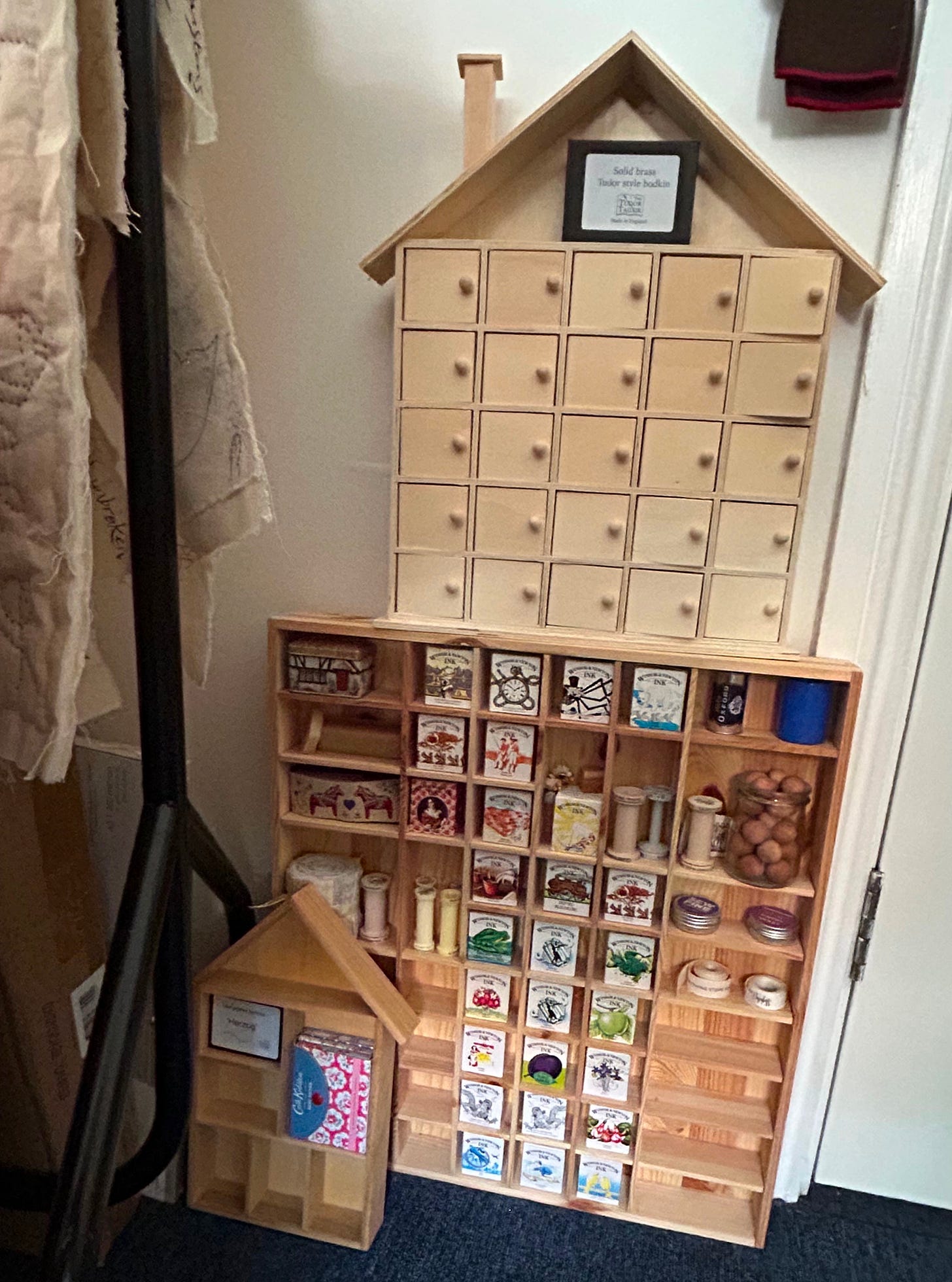 Wooden display racks filled with small objects including ink boxes, cotton reels,and ribbons. 