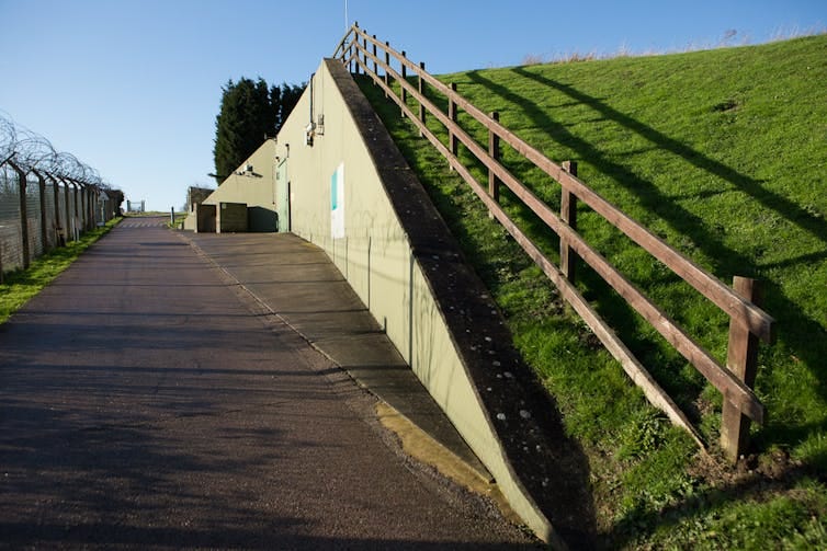 The side entrance to a bunker showing a hill and barbed wire fencing