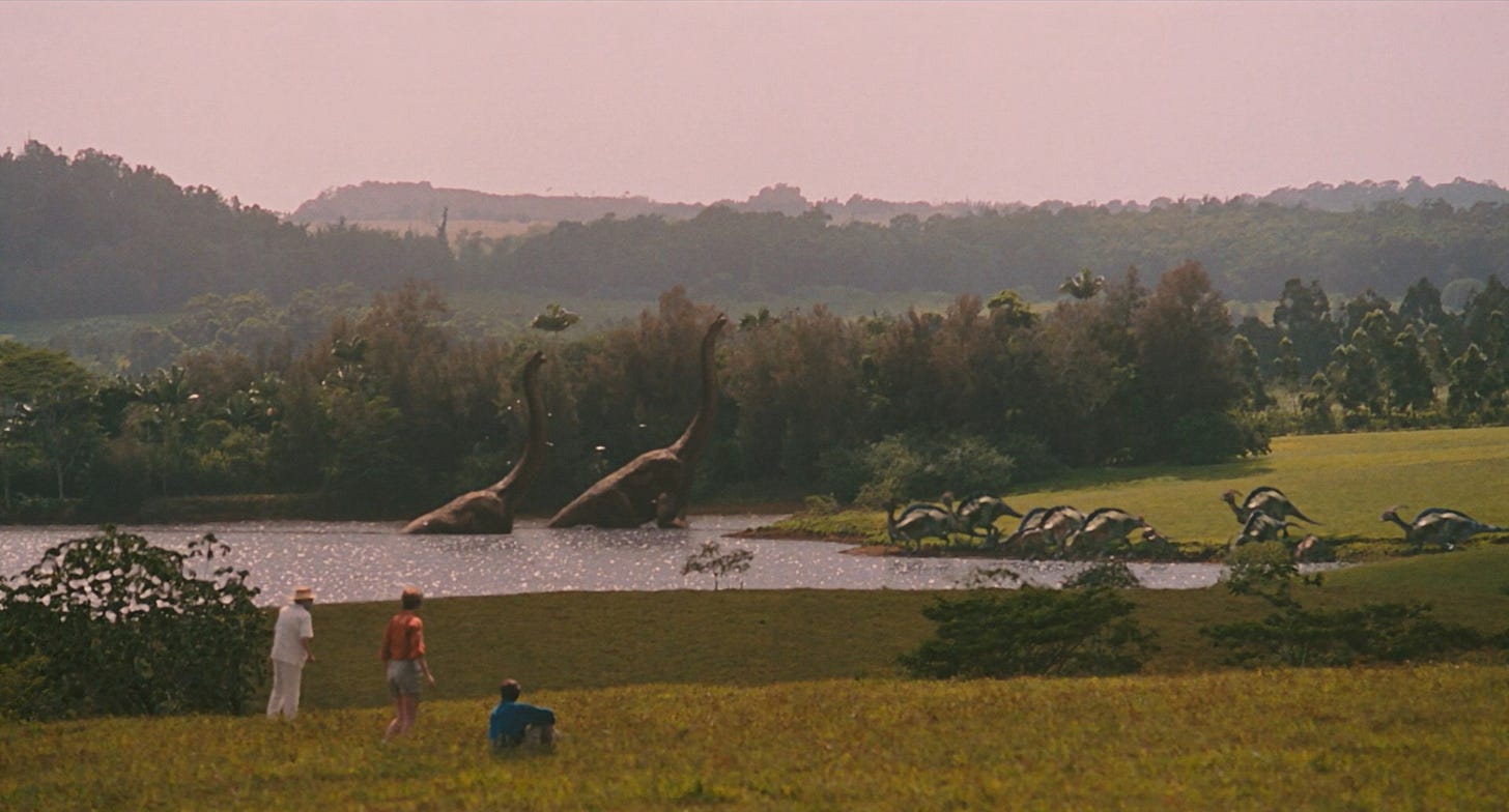 Three people, an old man and a young couple, observe dinosaurs bathing and drinking in a lake