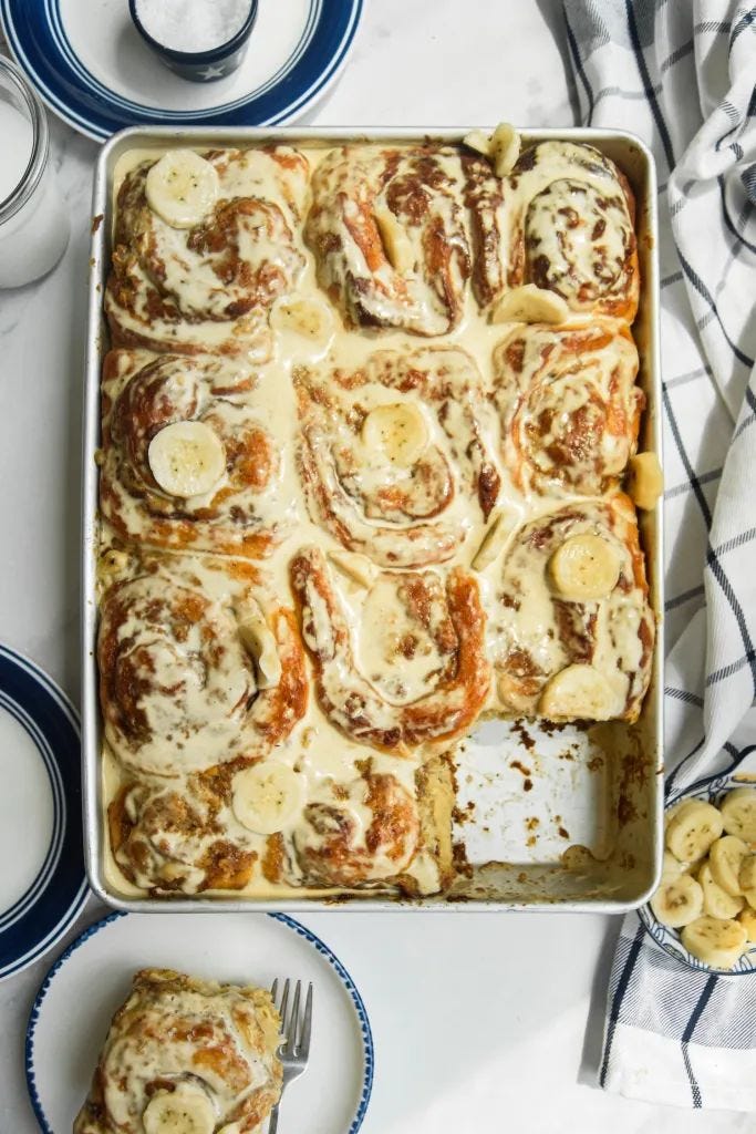 This may contain: a casserole dish with bananas and cinnamon rolls