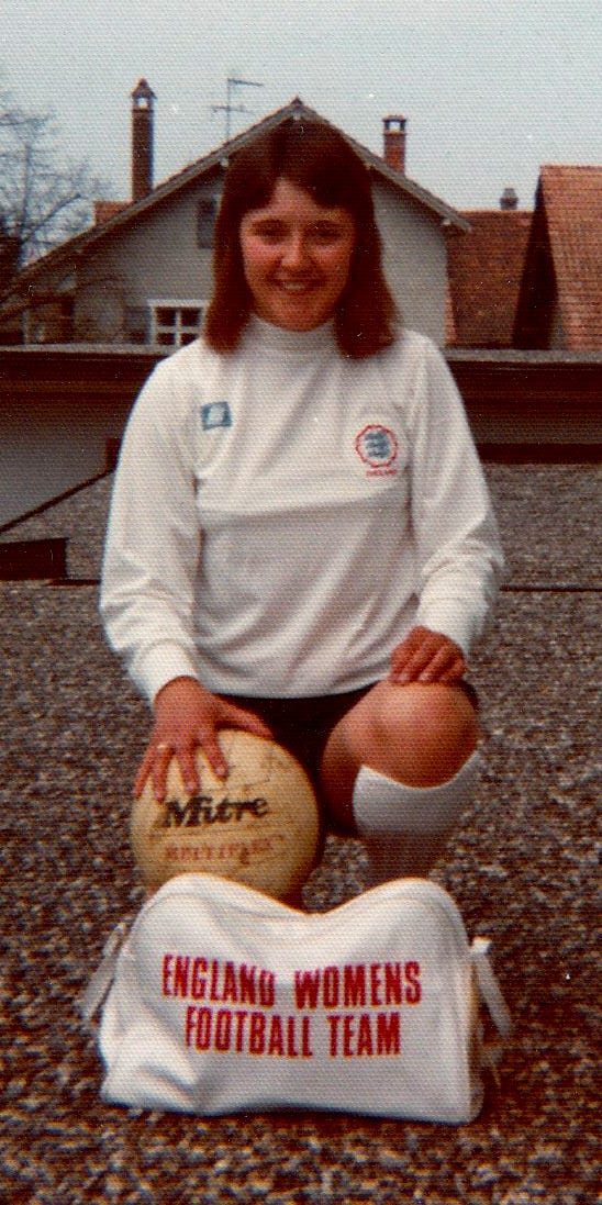 Carol Thomas, England captain in the 1980s, crouched down with her England bag and a ball.