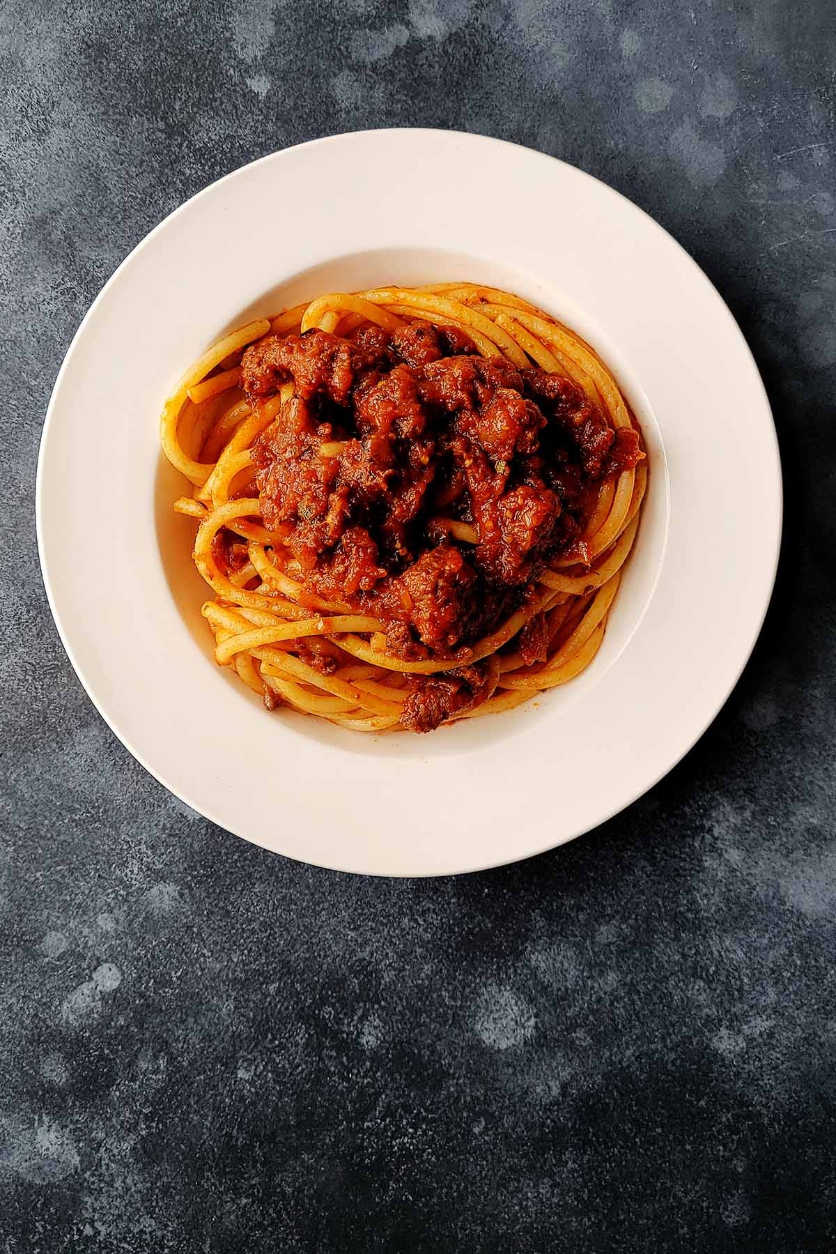 A plate of bucatini with red sauce. 