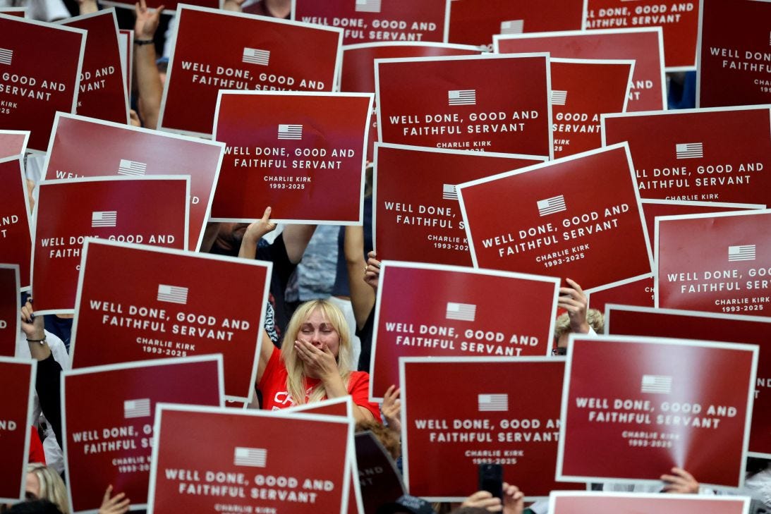 People hold up banners as they gather to attend Charlie Kirk's memorial service in Glendale, Arizona, on Sunday.