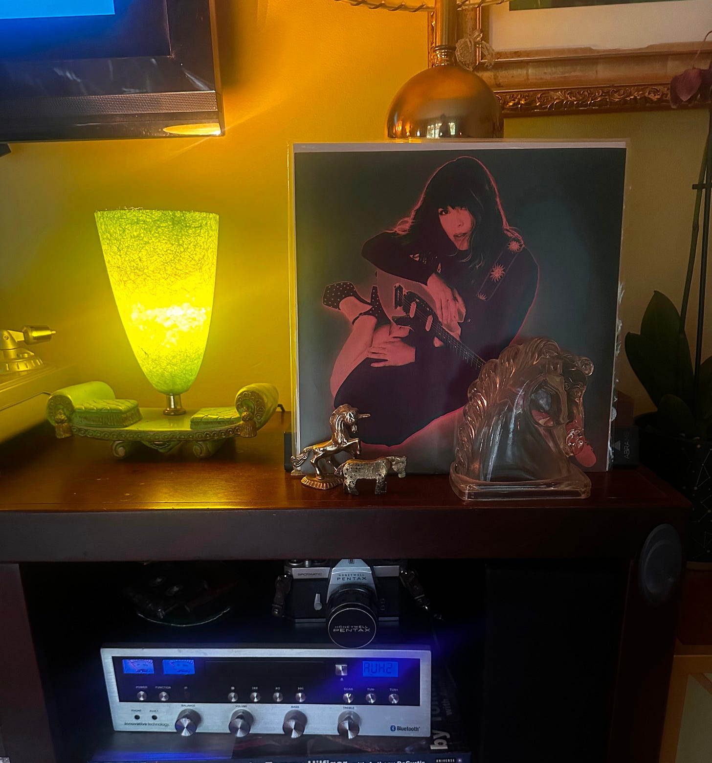 photo of a living room console with a vinyl record of a woman sitting sideways in a dress and platform heels holding a guitar